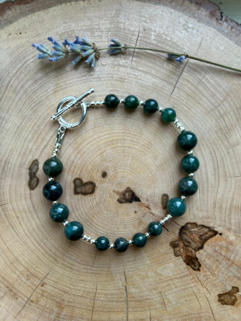 Moss agate breathwork bracelet with 925 silver-plated toggle clasp on a wooden slice with lavender